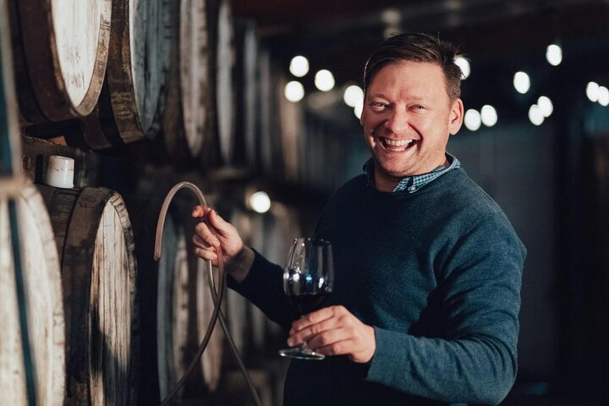 Un hombre sosteniendo una copa de vino en una bodega