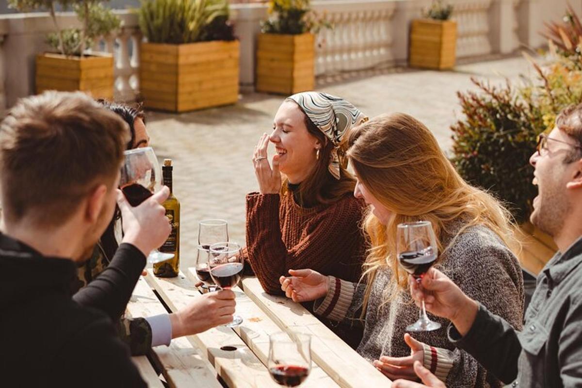 skupina ljudi, ki sedijo za mizo in pijejo vino