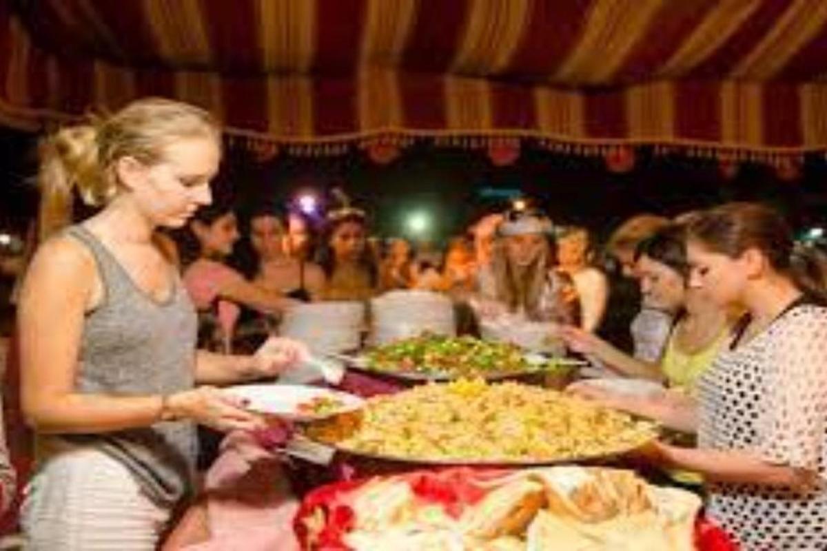 hópur fólks stendur við borð með pizzur