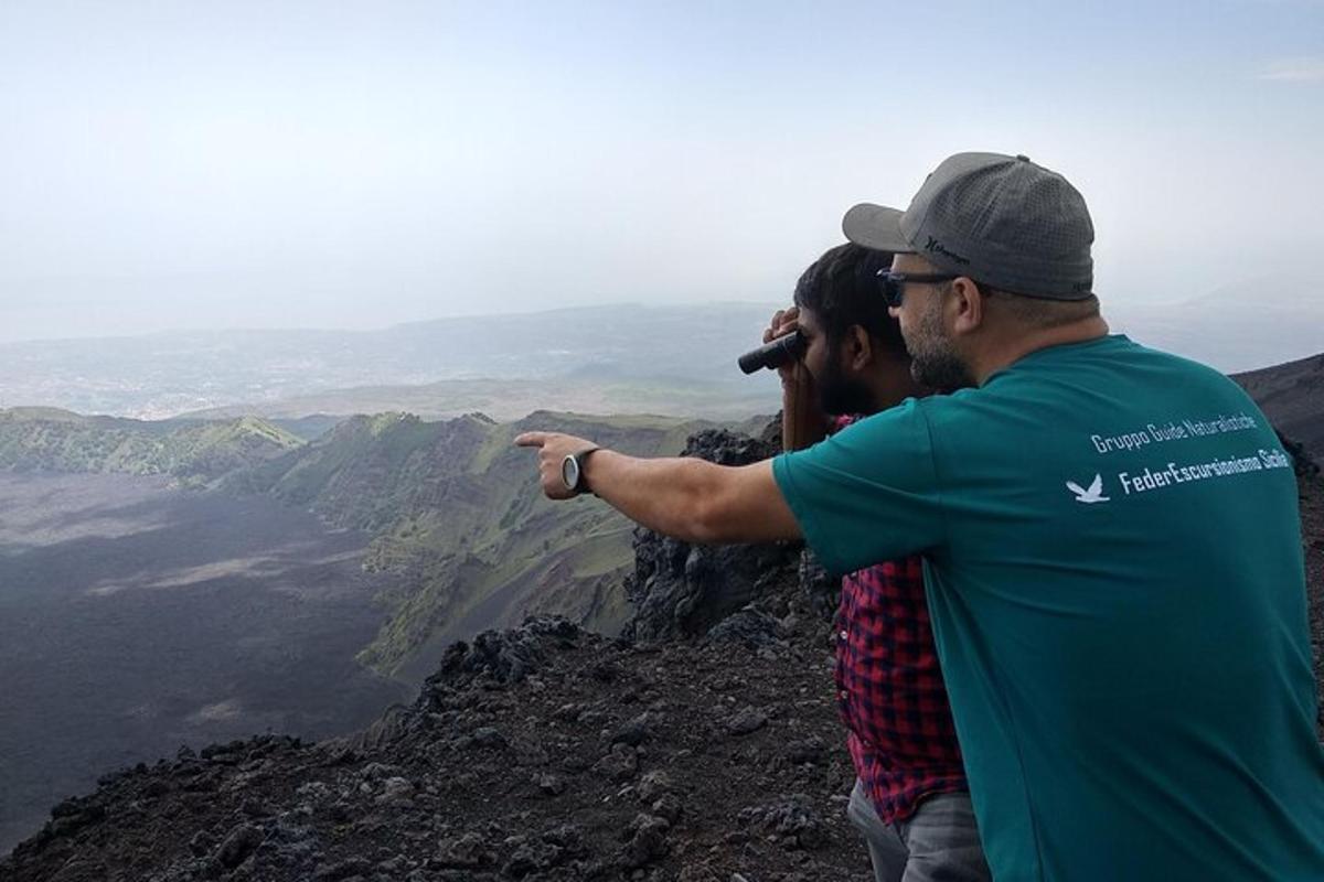 seorang lelaki menunjuk ke arah pemandangan dari puncak gunung