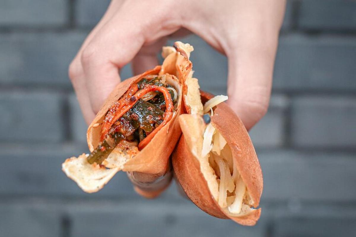käsi, mis hoiab kuklis hot dogi
