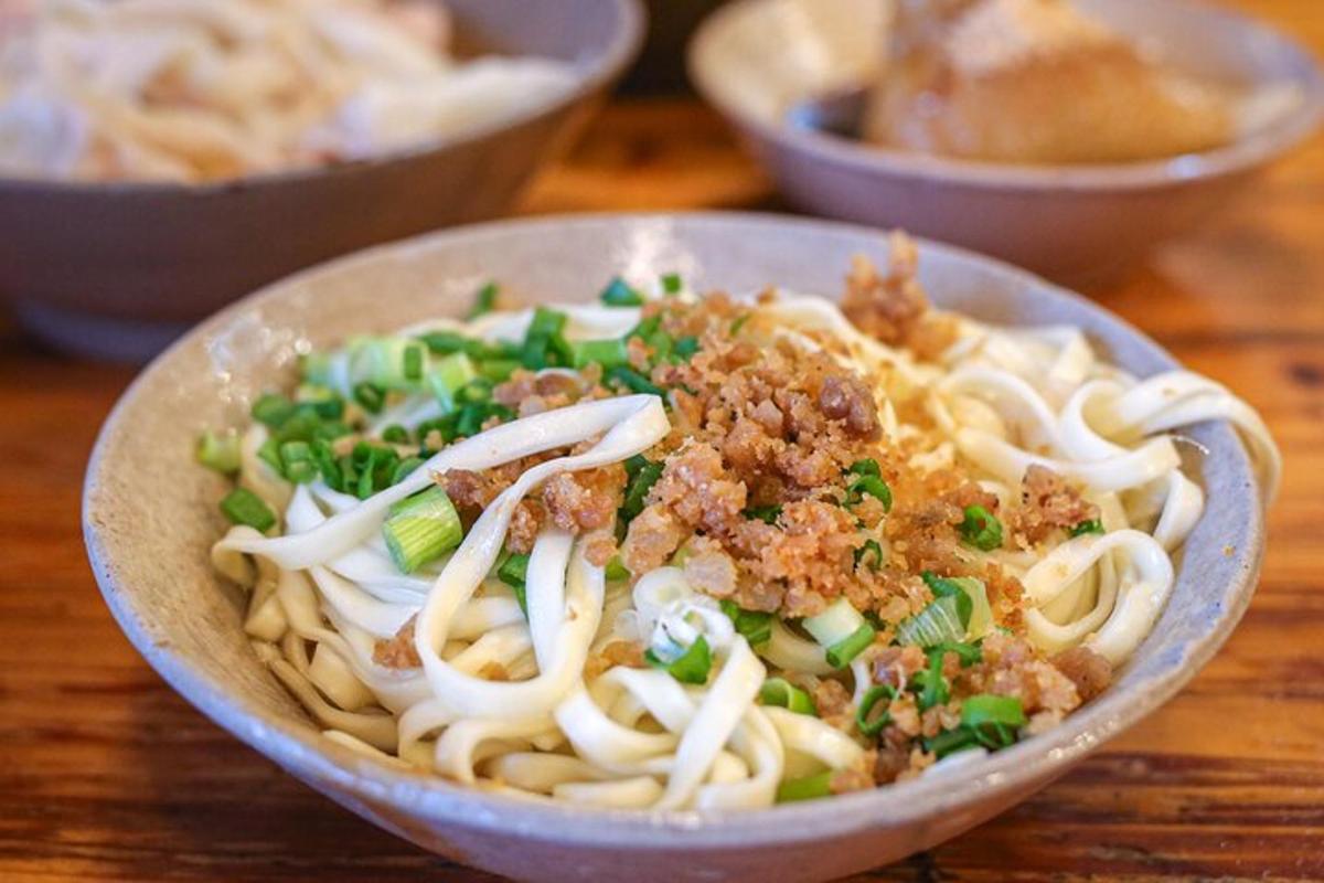 a bowl of pasta with meat and vegetables on a table