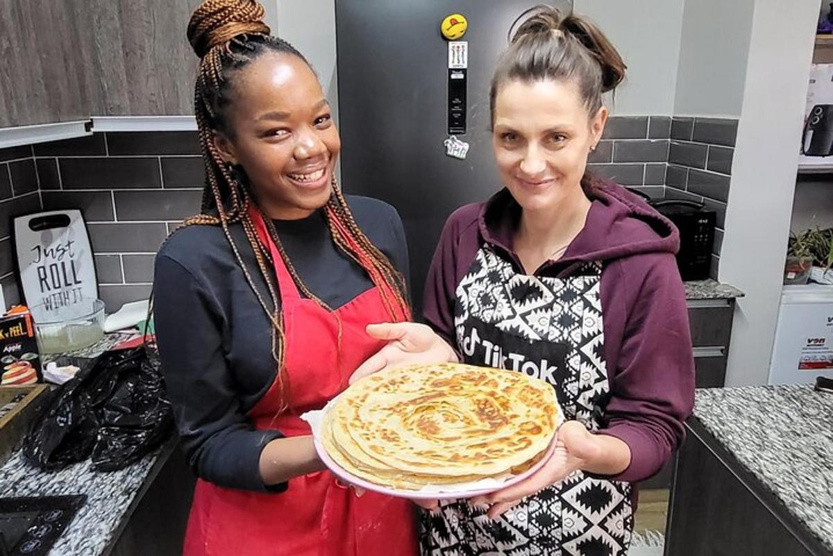 two women standing in a kitchen holding a plate of food