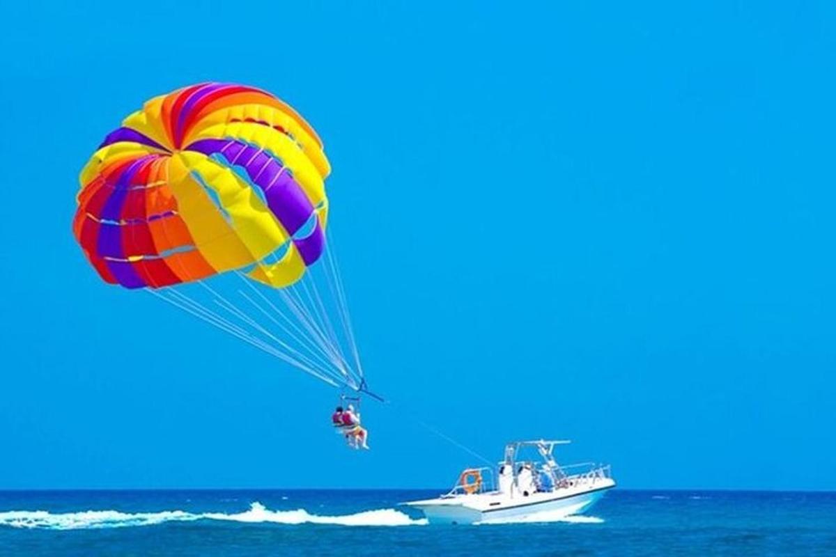 una persona que viaja en paracaídas sobre el océano con un bote