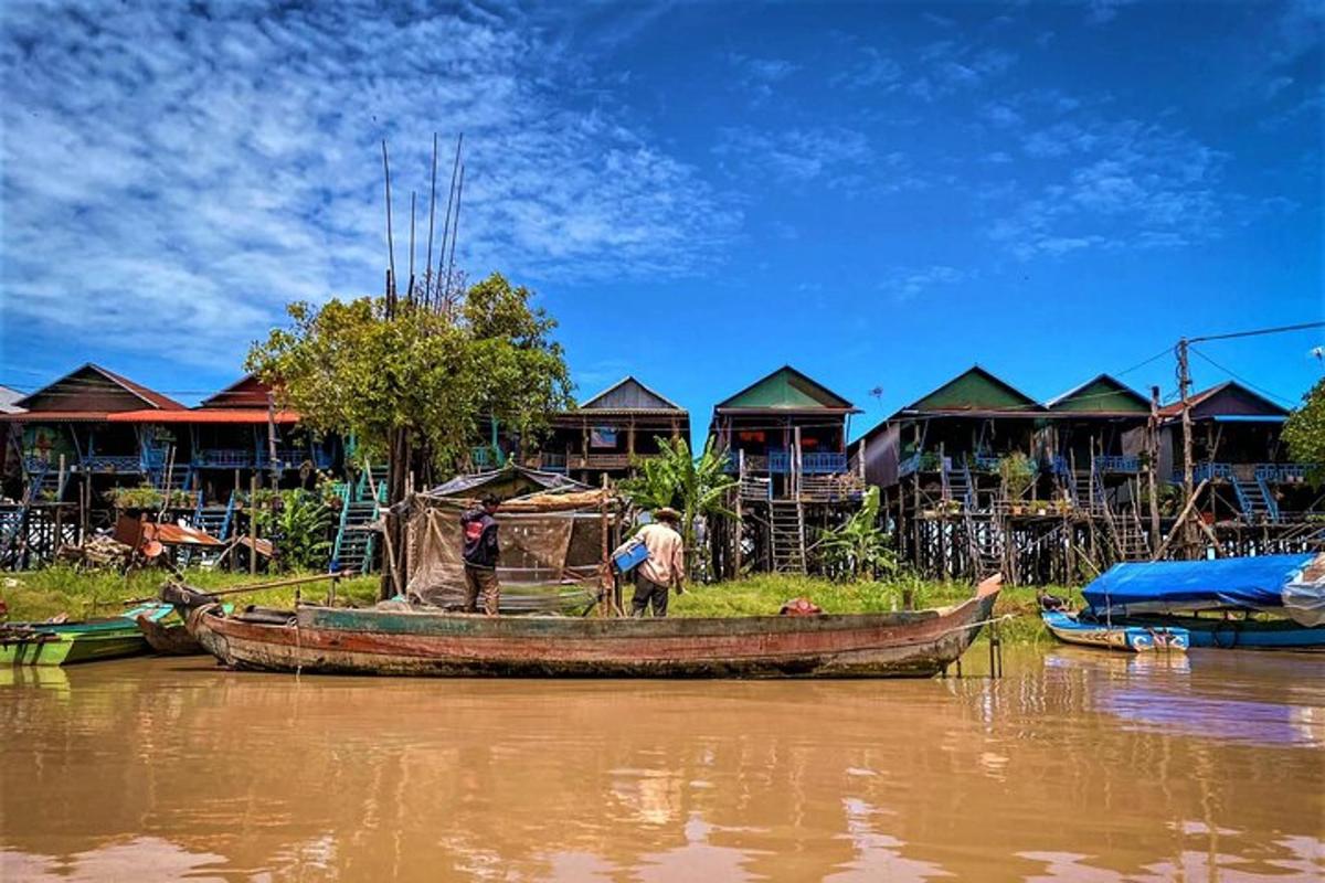 seorang lelaki berdiri di dalam bot di atas sungai dengan rumah