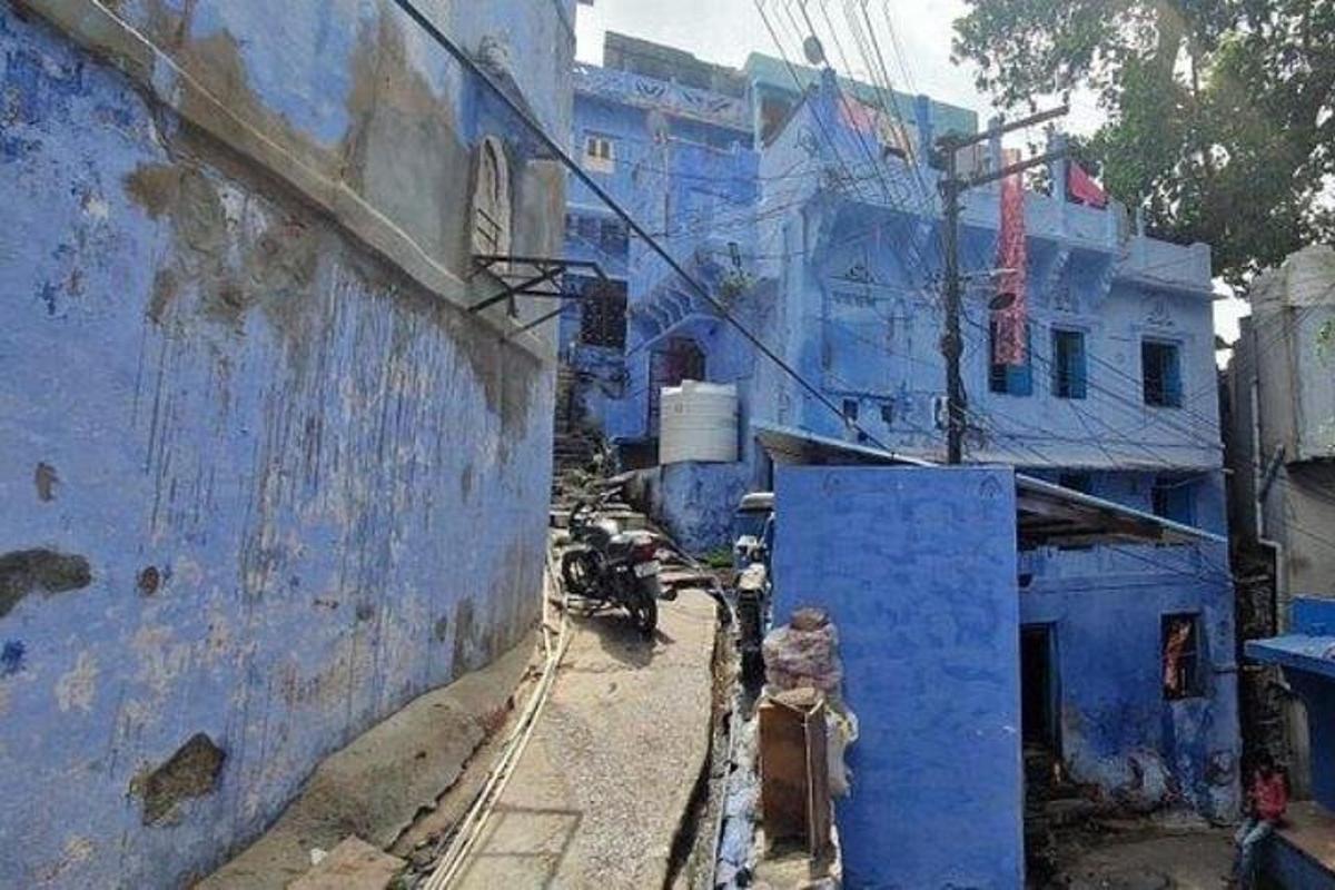 an alley with blue buildings and a motorcycle on a street