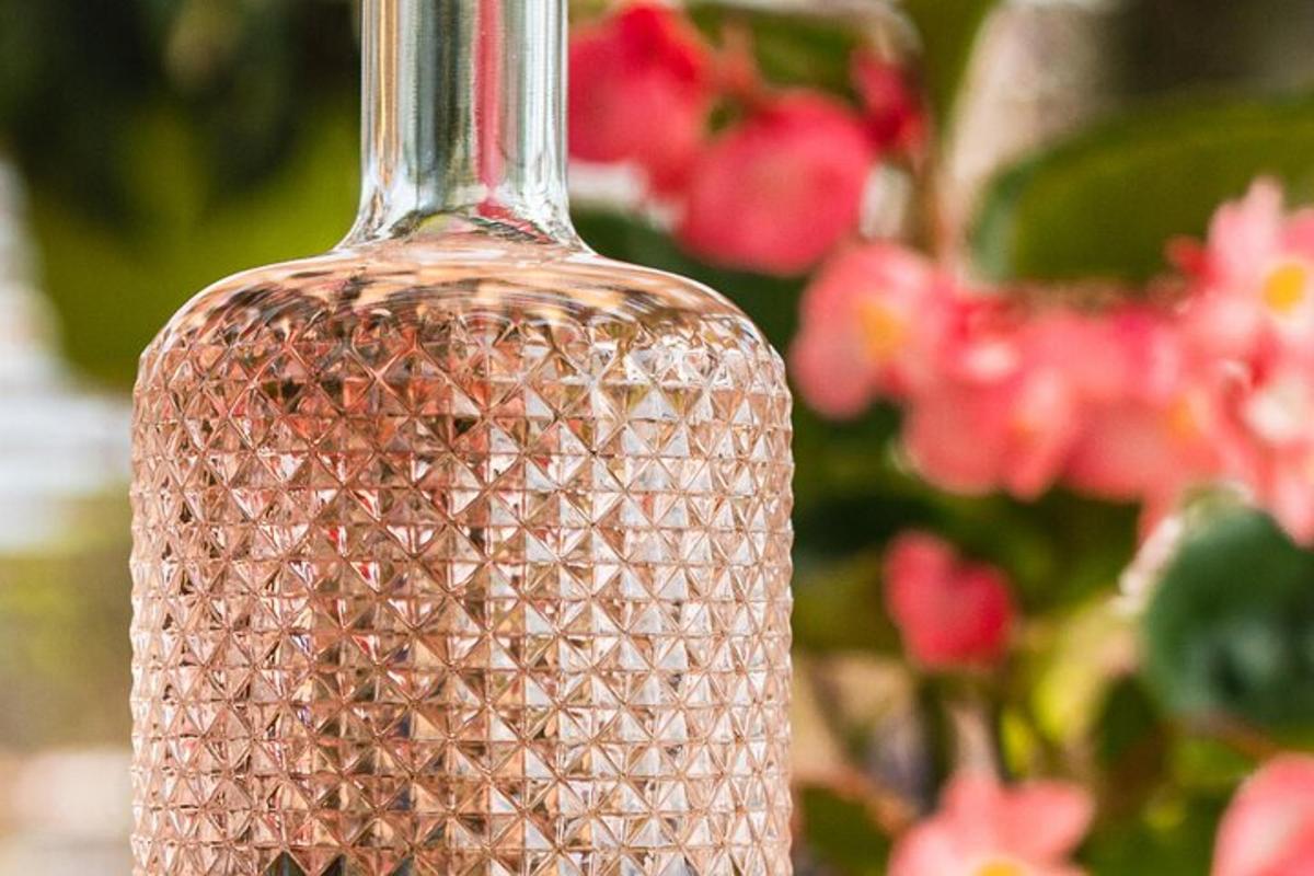 un gerro de vidre transparent amb flors roses al fons