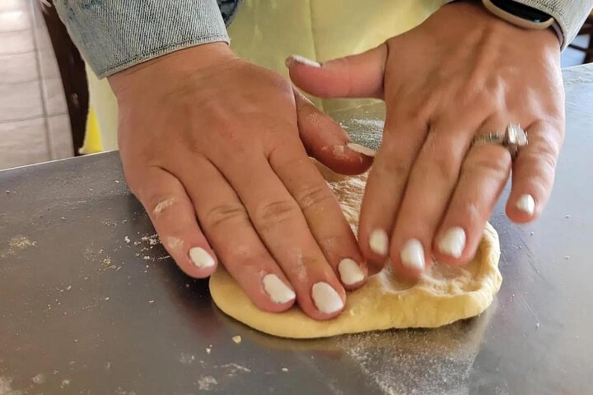 eine Person mit ihren Händen auf dem Teig auf einer Theke