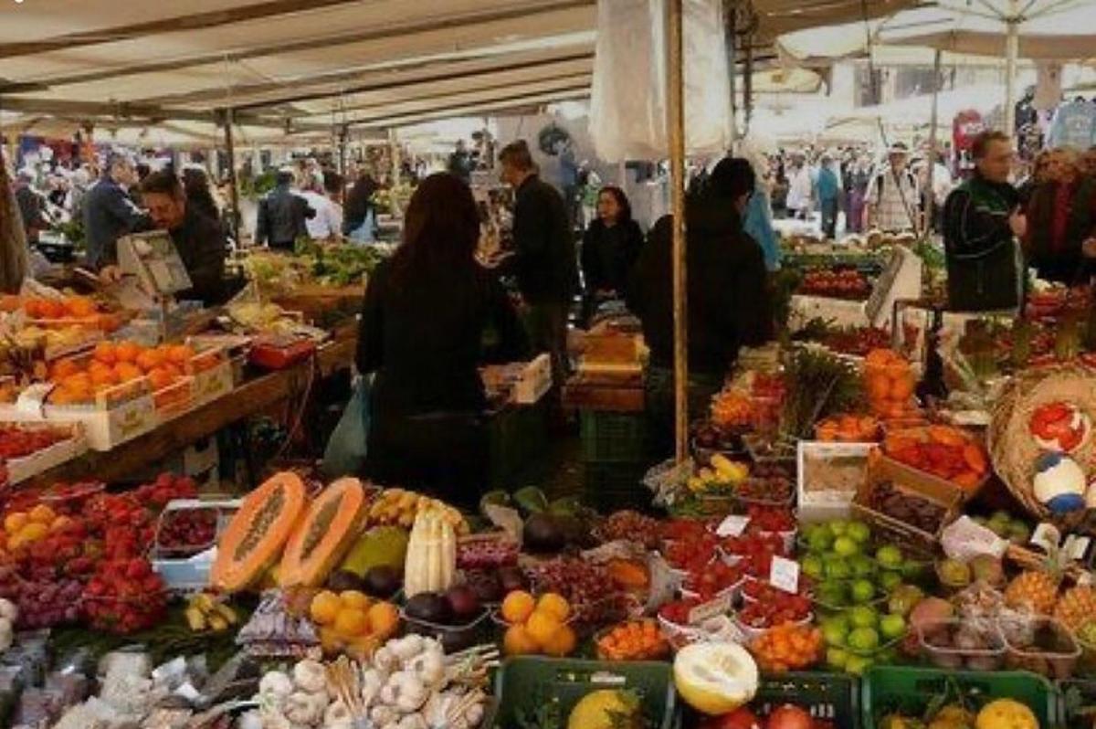 un grup de oameni care stăteau într-o piață cu fructe și legume