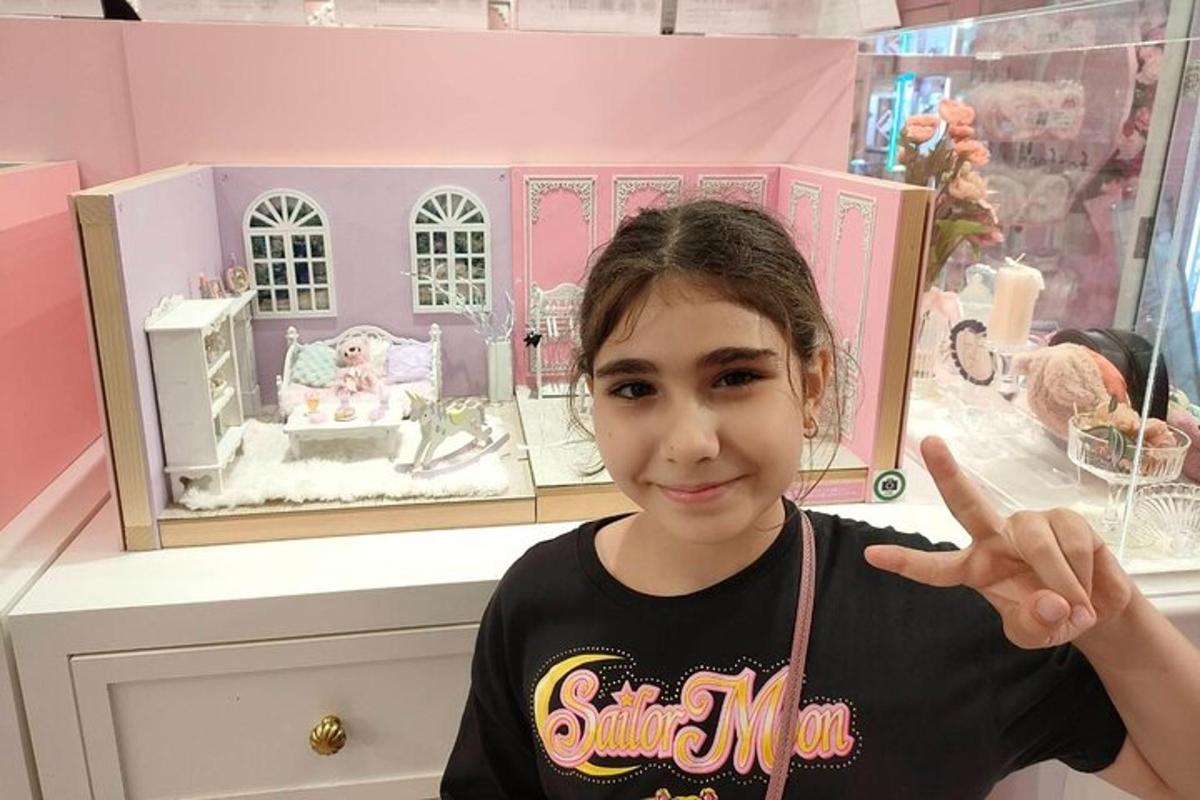 a young girl points at a doll house in a store