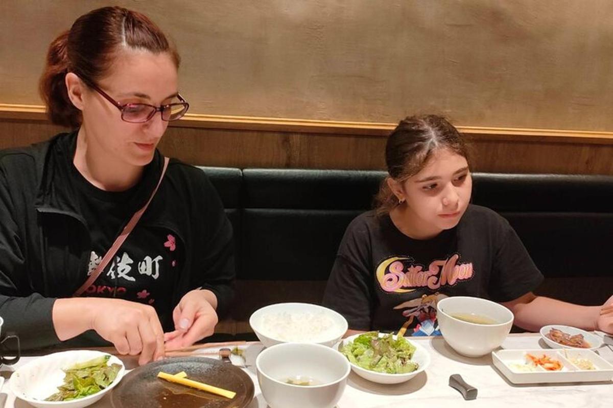 Una mujer y una niña sentadas en una mesa comiendo comida