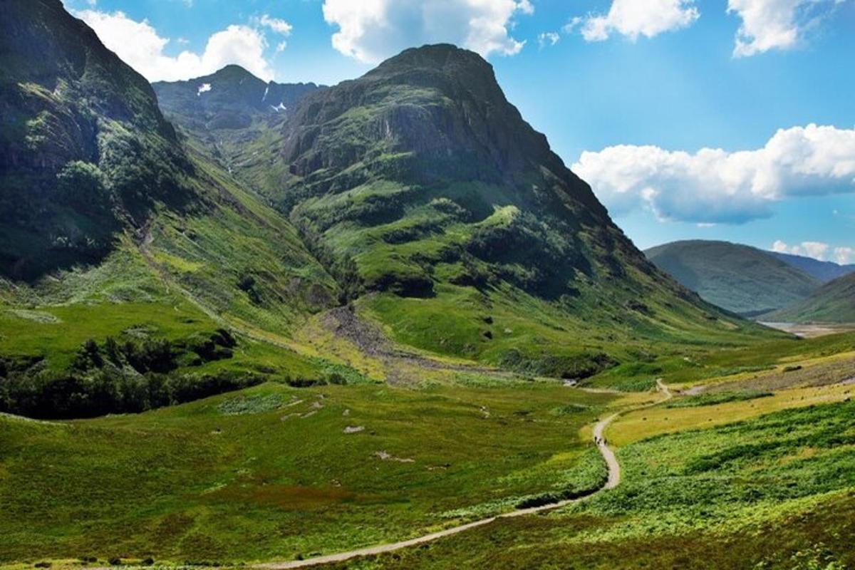 una vall verda amb un camí de terra a les muntanyes