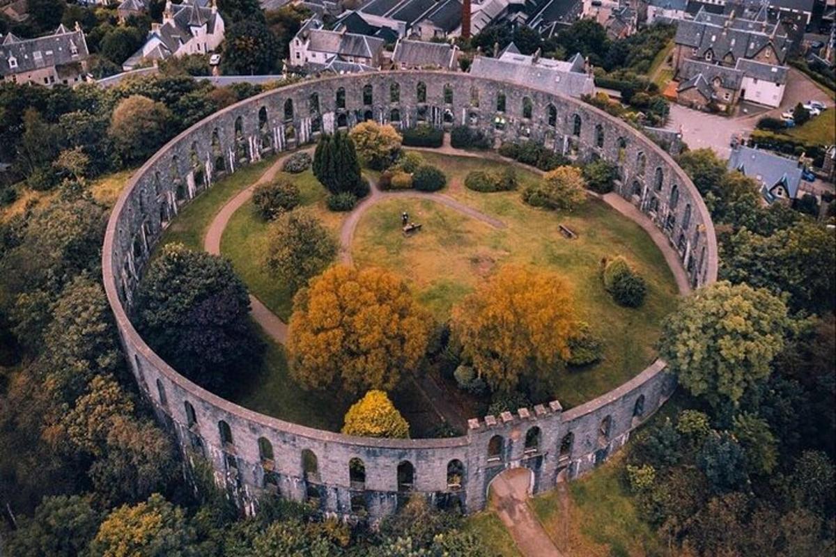 un vecchio edificio su una collina con alberi e case