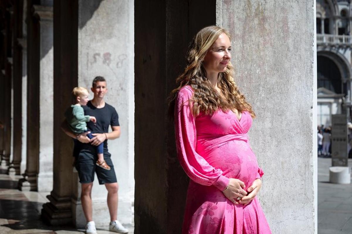 en gravid kvinne som står ved siden av en søyle med en mann og en baby