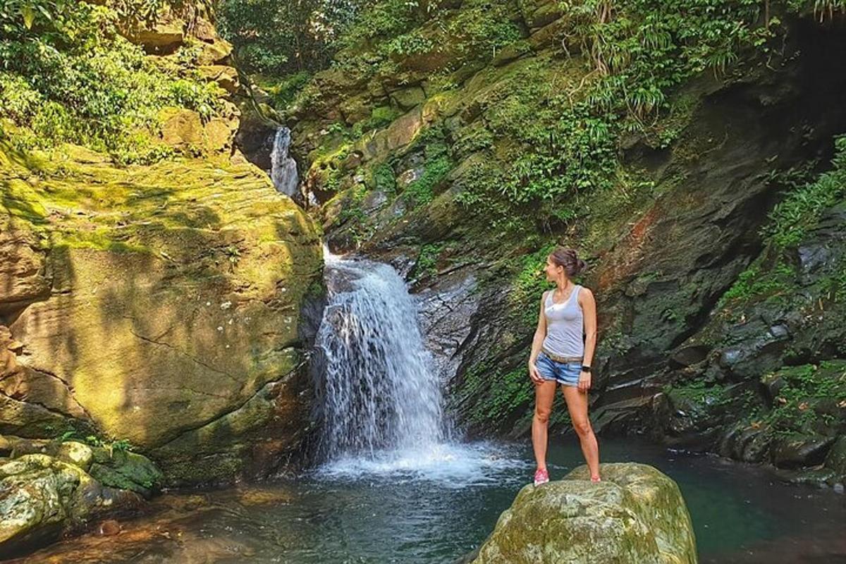 kona stendur á steini fyrir framan foss