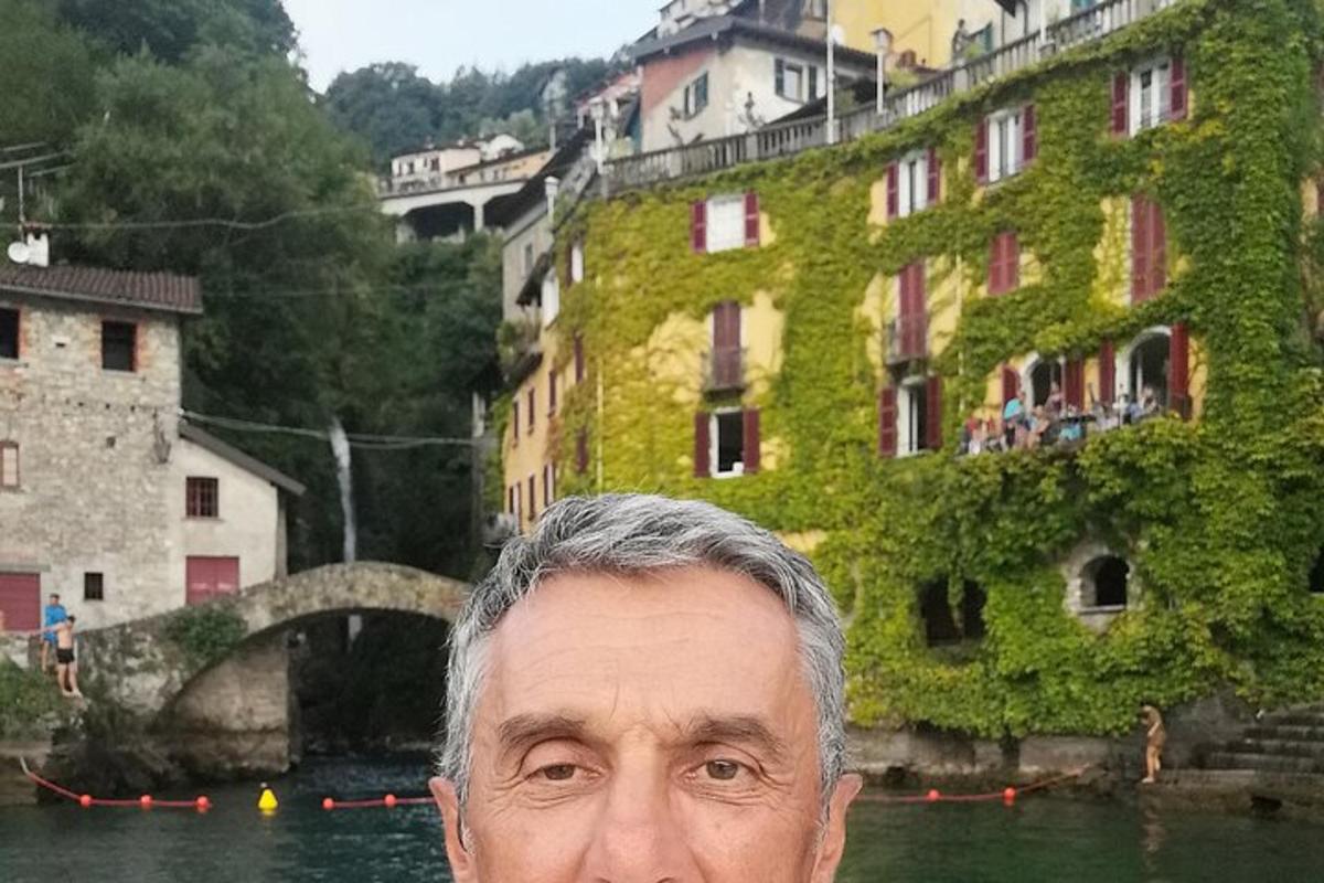 Un hombre parado frente a un río con un edificio.