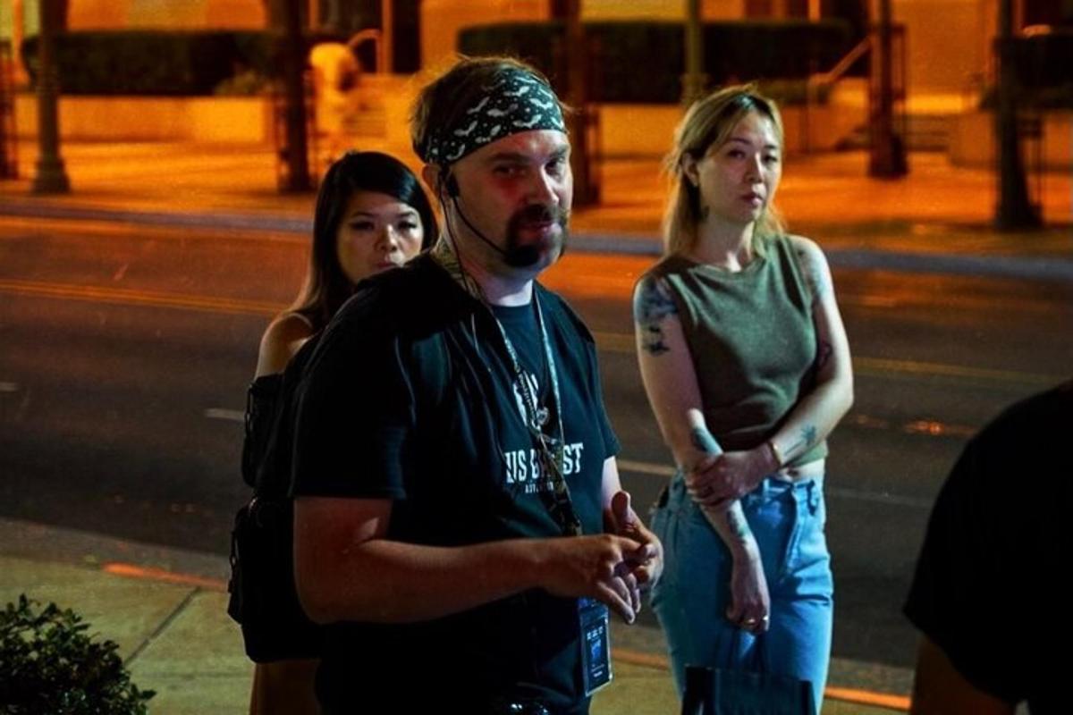a man with a bandanna on his head standing next to two women