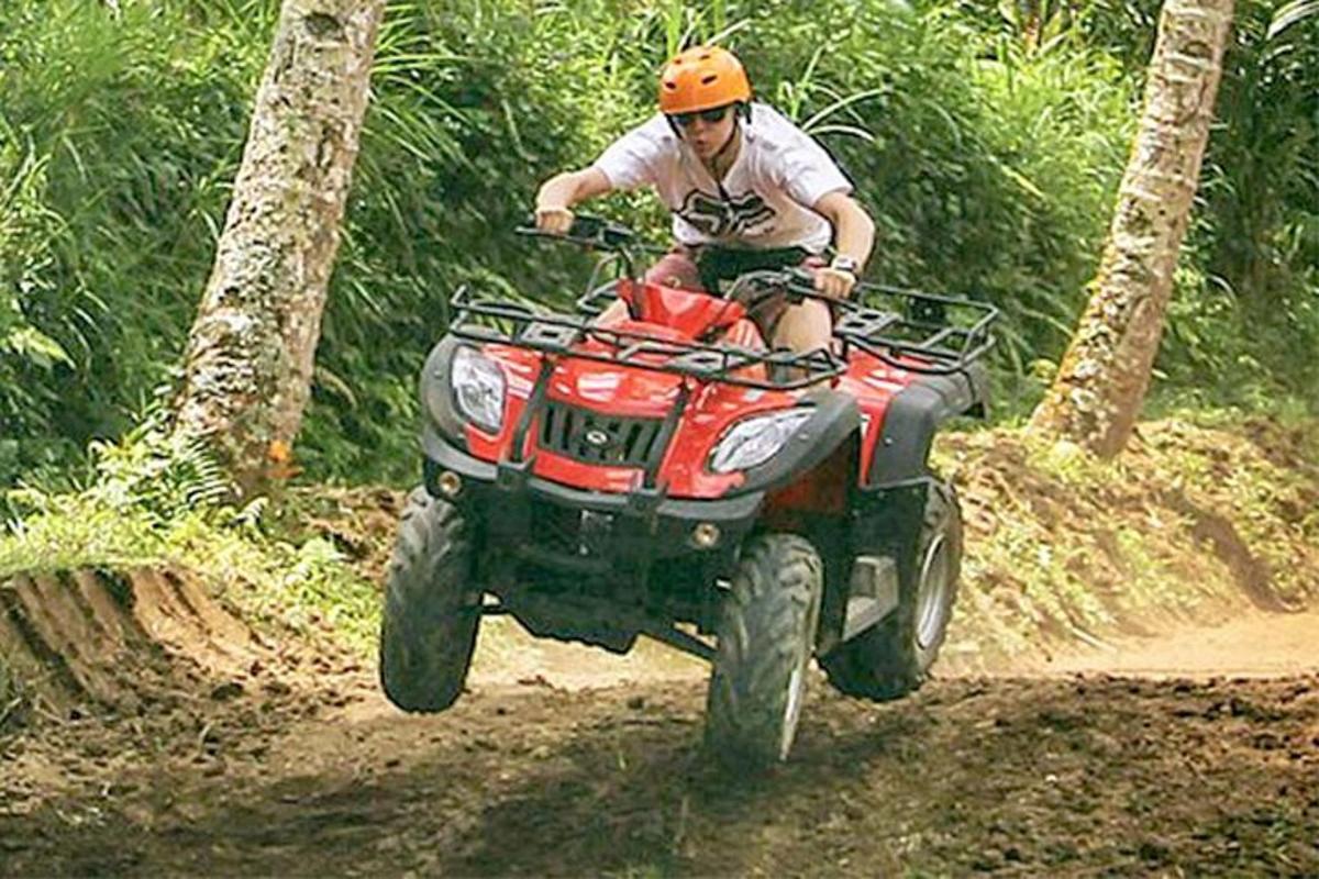 một người đàn ông đang lái xe bốn bánh trên đường mòn đất