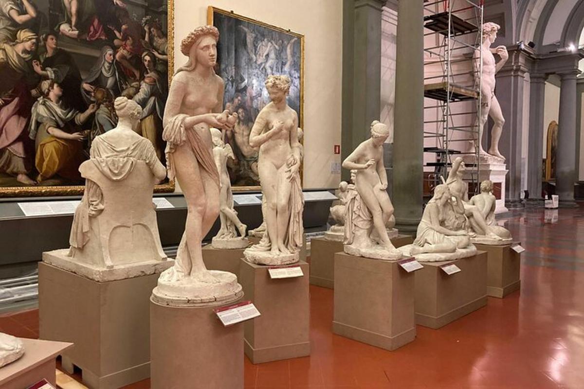 un gruppo di statue in un museo con un dipinto