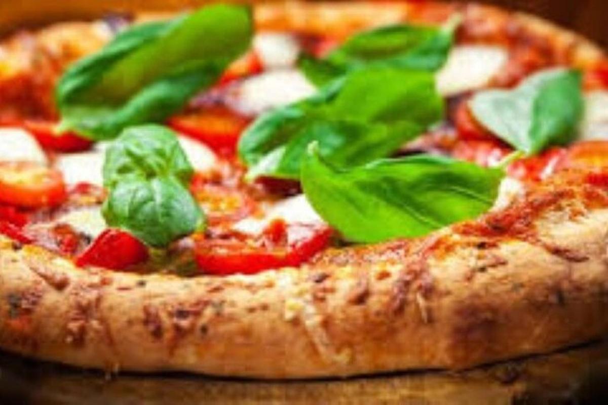 Una pizza con hojas verdes encima.