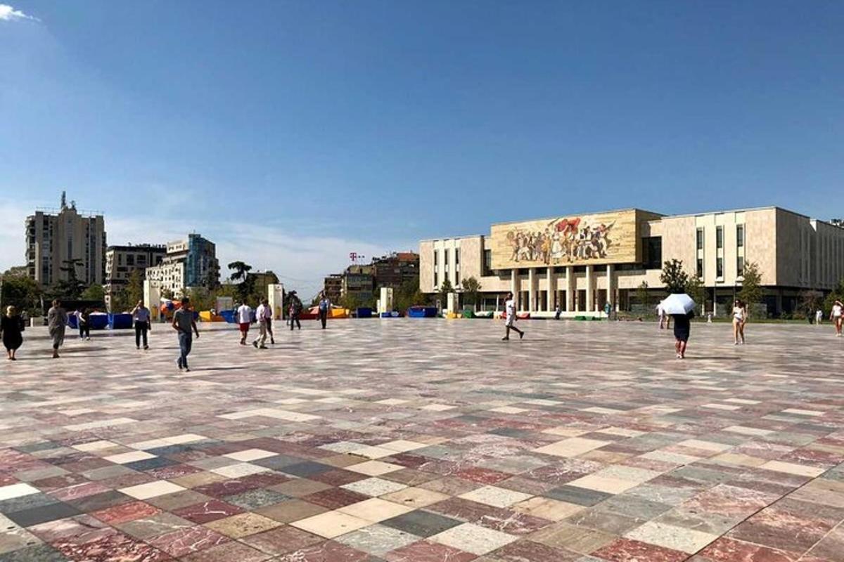 un gruppo di persone che camminano in una piazza con edifici