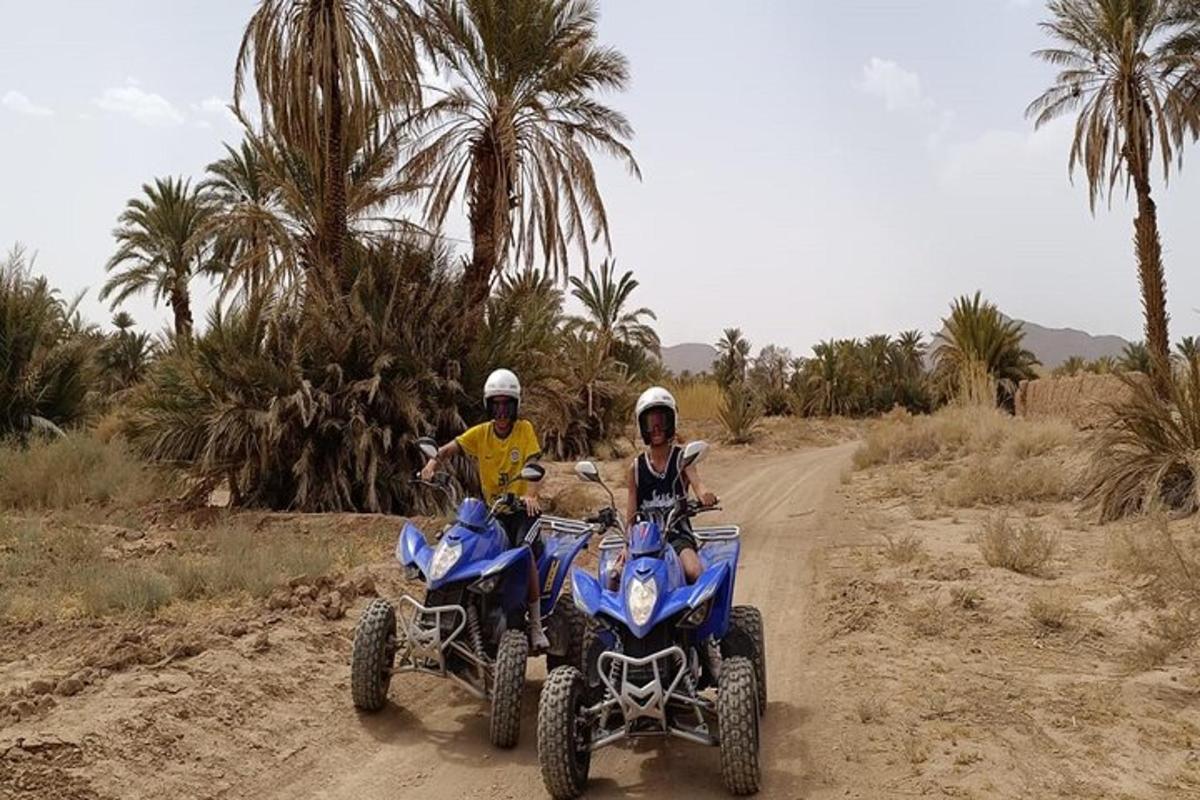 two people on atvs on a dirt road with palm trees