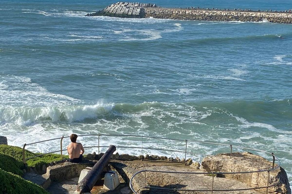 seorang pria duduk di tangga sambil melihat ke arah laut