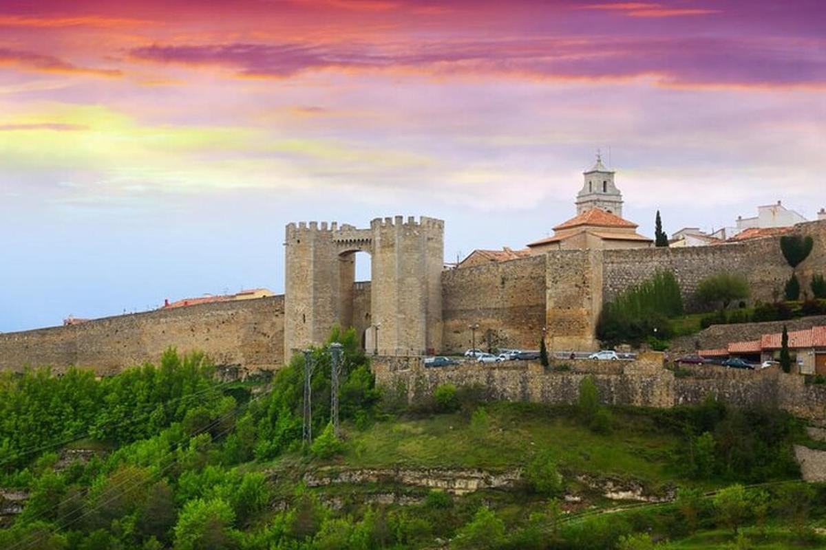 Un antiguo castillo en una colina con una puesta de sol