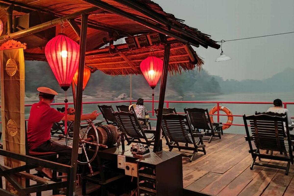 a man sitting on the deck of a boat with red lanterns