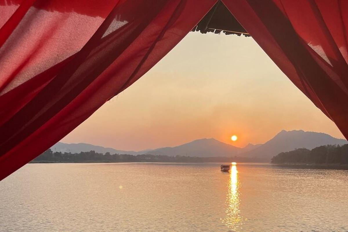 a view from a tent of a boat in the water at sunset