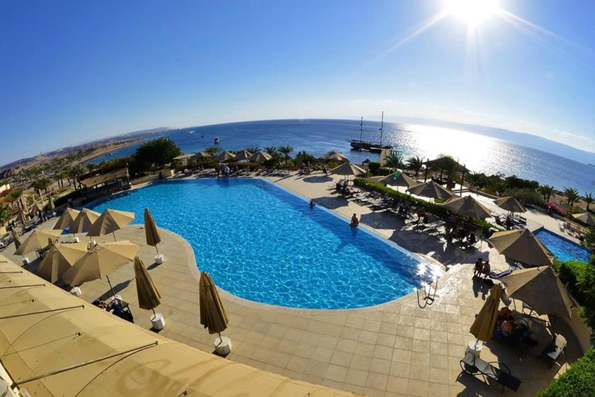 a large swimming pool with umbrellas and the ocean