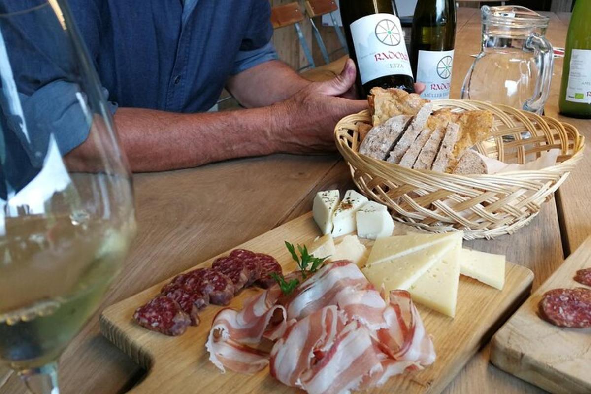a man holding a bottle of wine and a table with cheese and meats