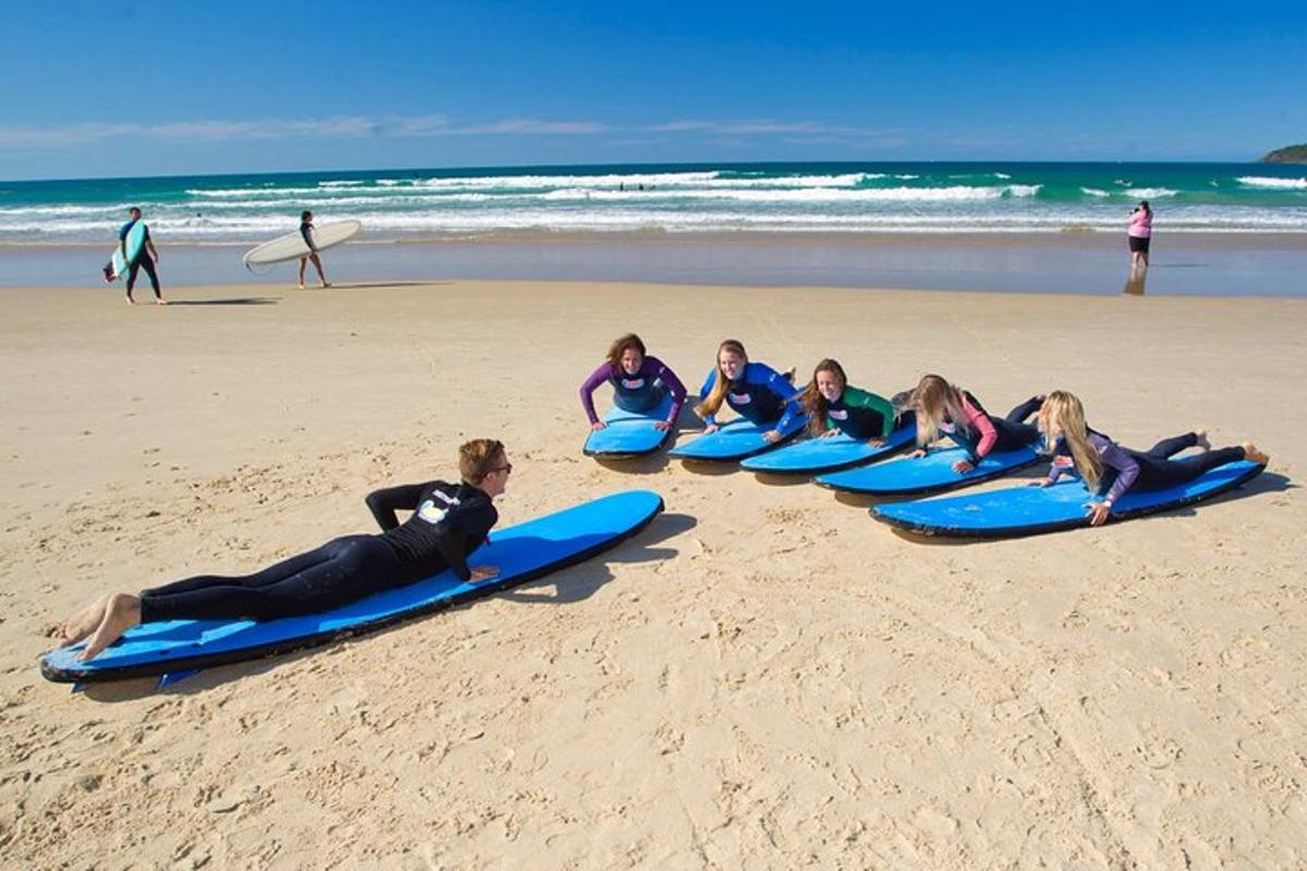 un grup de fete întinse pe plăci de surf pe plajă