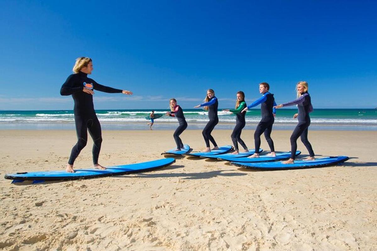 a group of people standing on surfboards on the beach