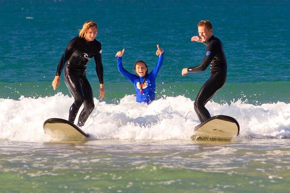 doi adulți și un copil pe plăci de surf în ocean