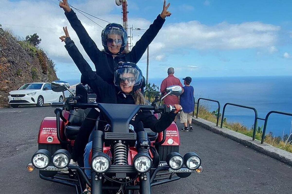 due persone in sella a una motocicletta con le braccia alzate