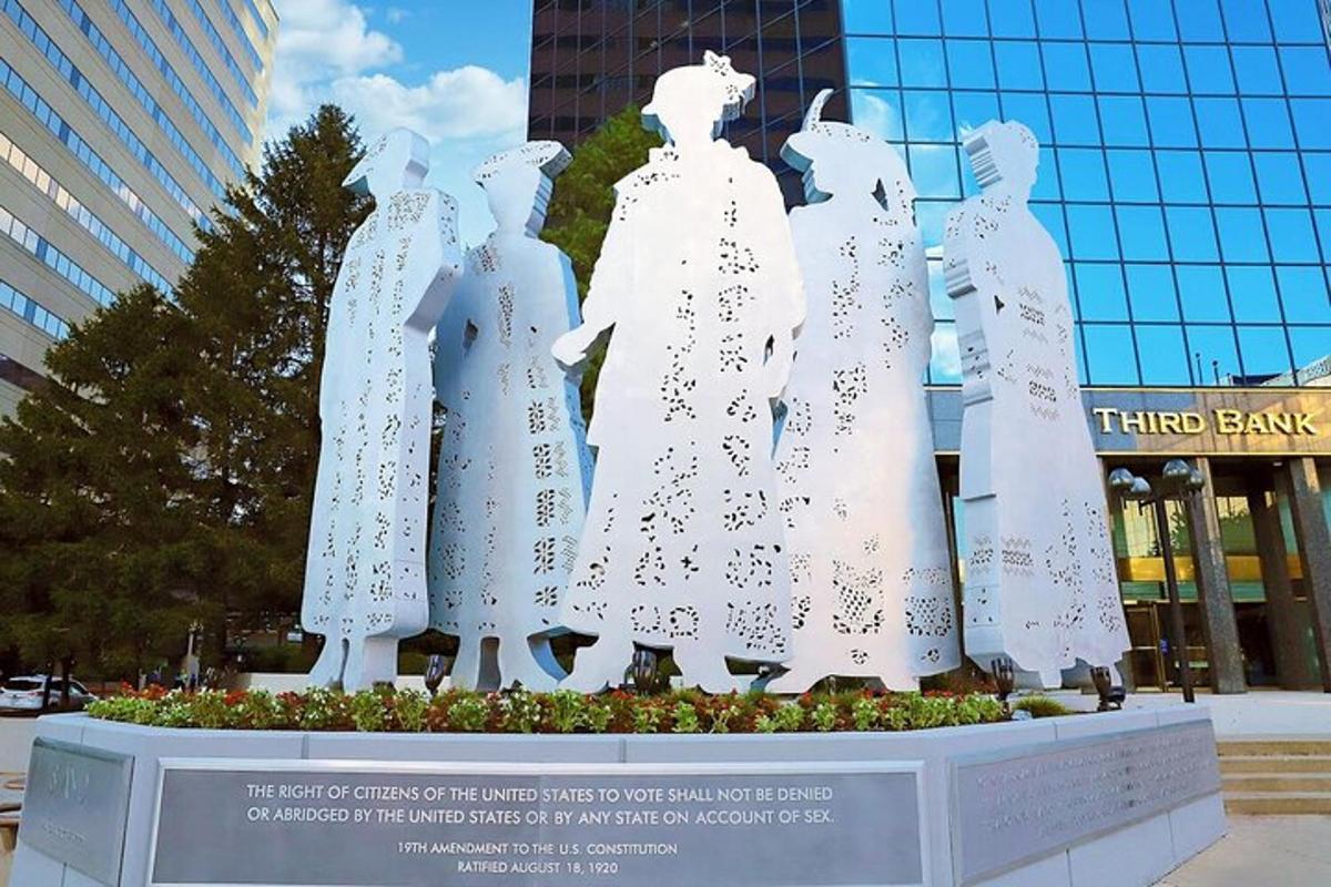 a statue of women in dresses in front of a building
