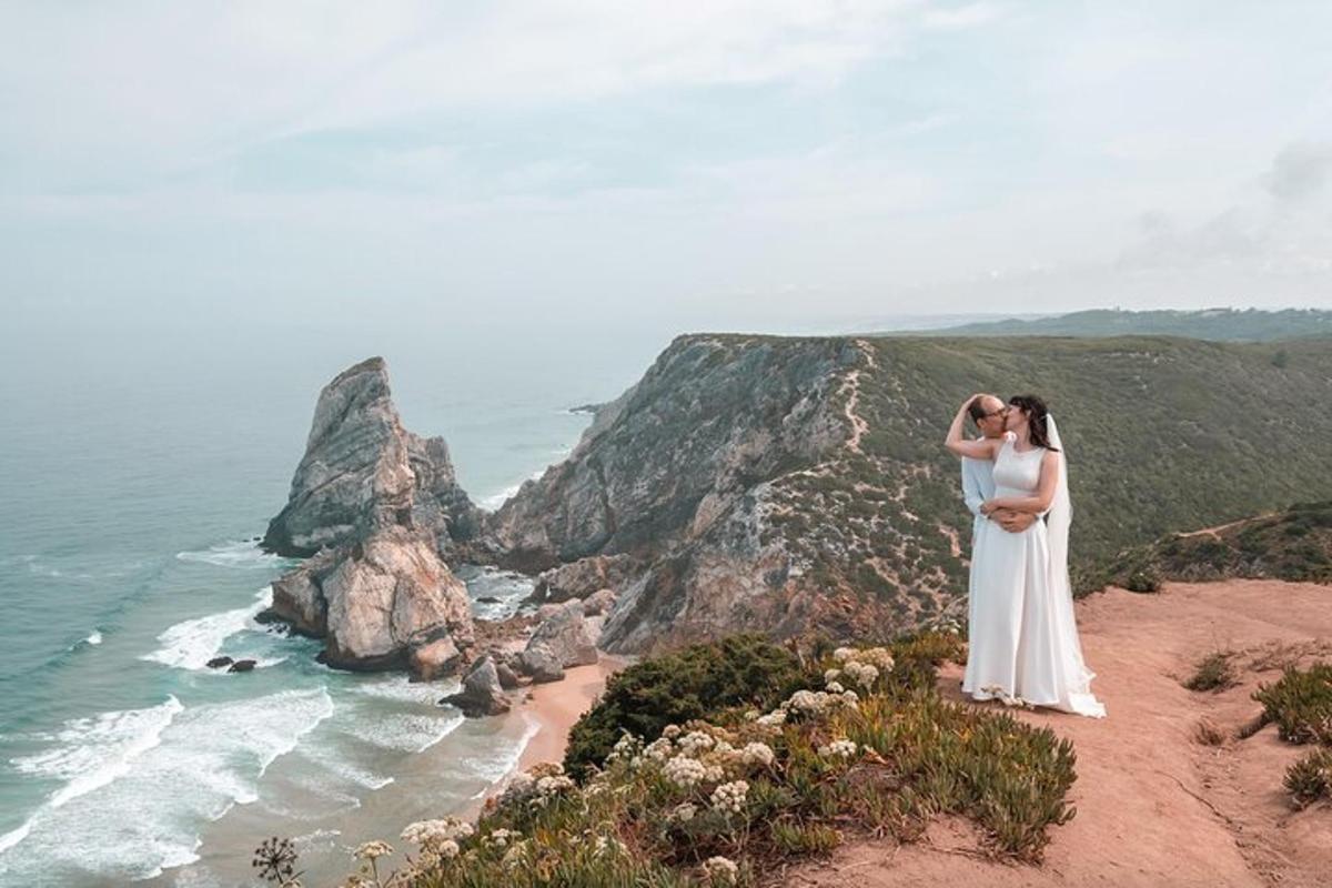 a bride and groom standing on a cliff overlooking the ocean
