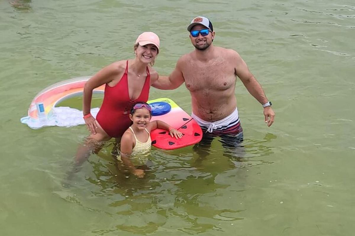 a man and a woman standing in the water with a surfboard