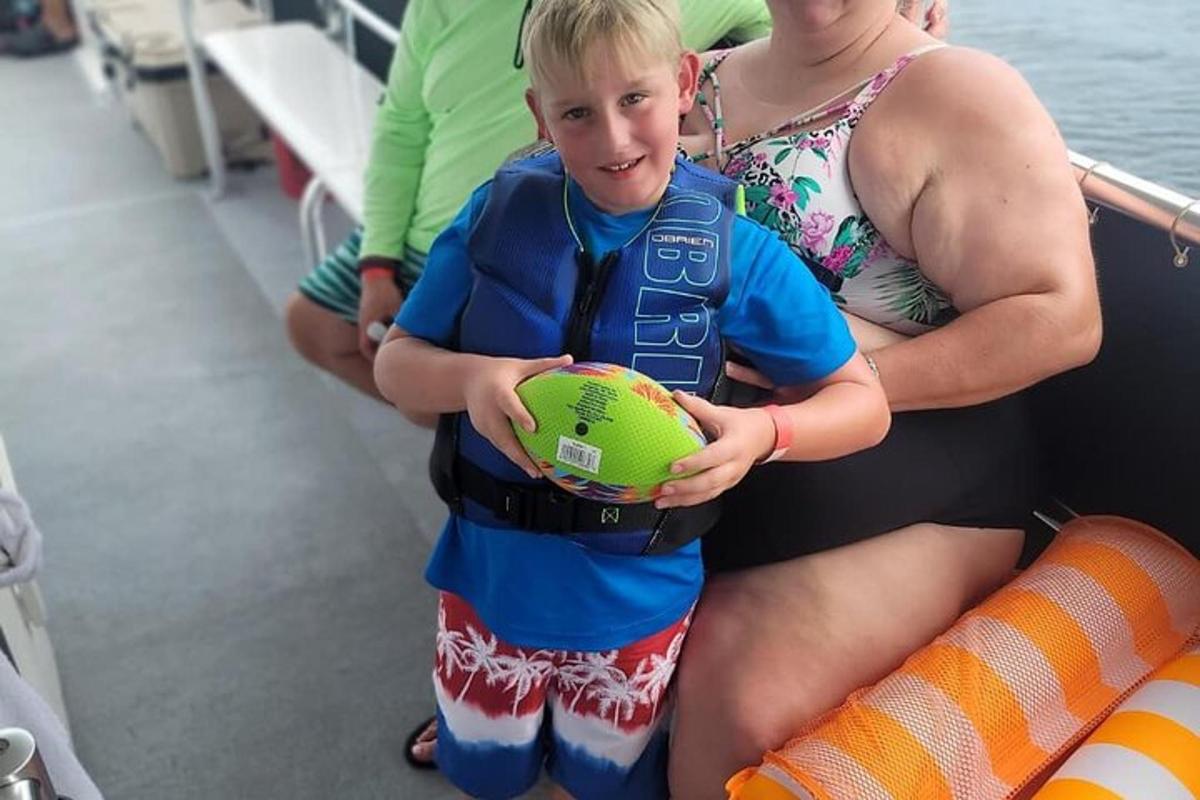 a young boy holding a ball on a boat