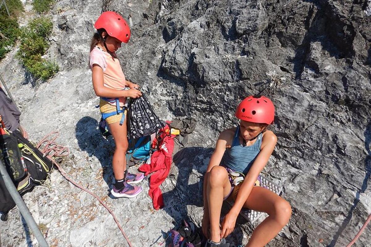 two girls wearing helmets on a rock wall