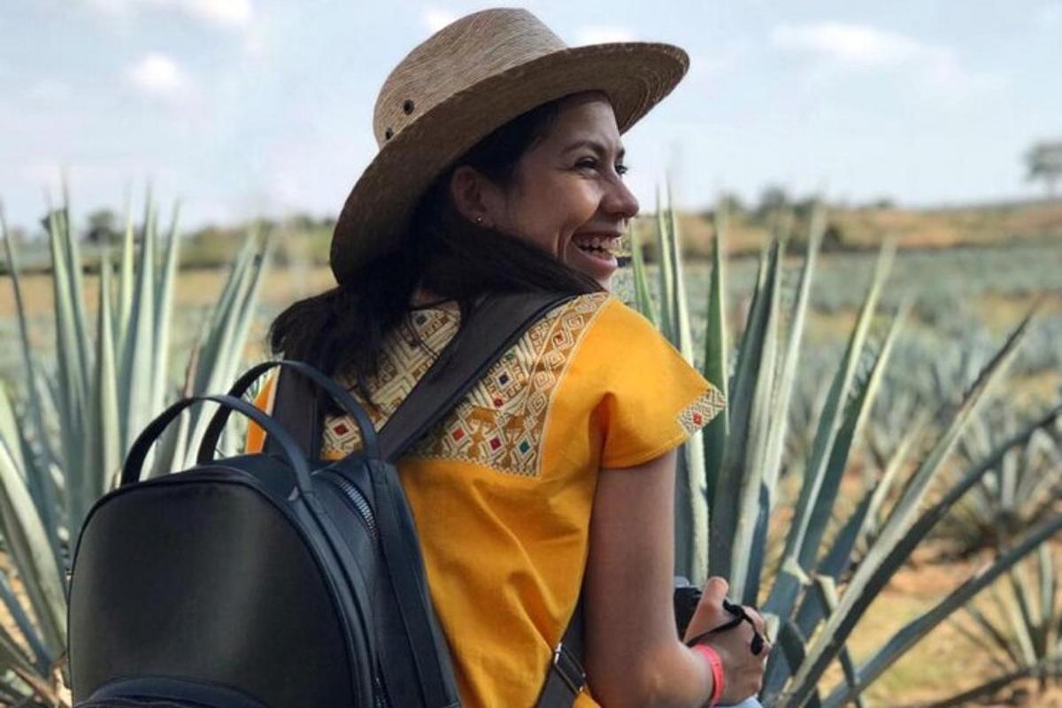 una donna che indossa un cappello e tiene in mano uno zaino
