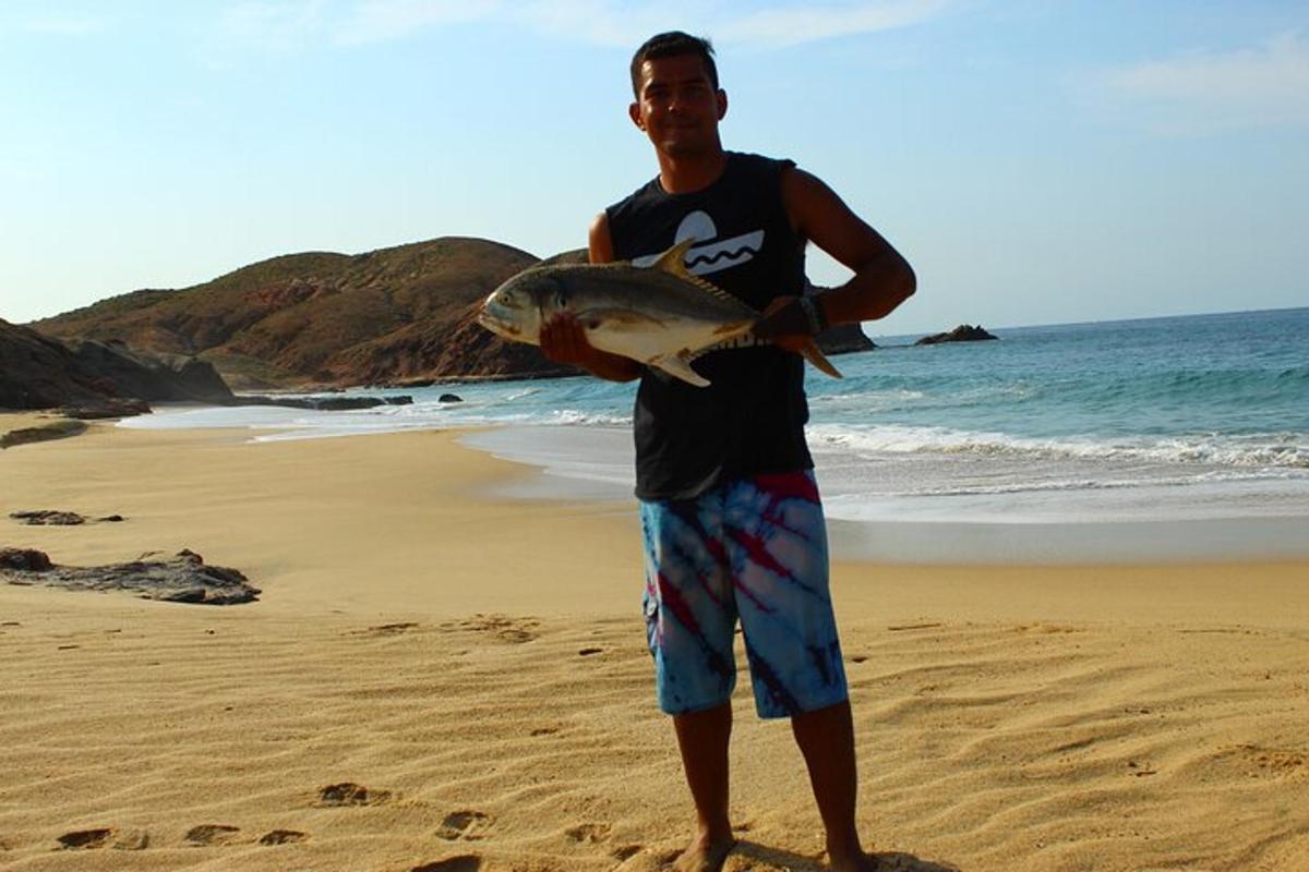 un home que sosté un peix a la platja