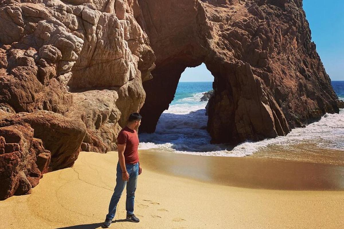 seorang lelaki berdiri di pantai berhampiran gerbang di dalam batu