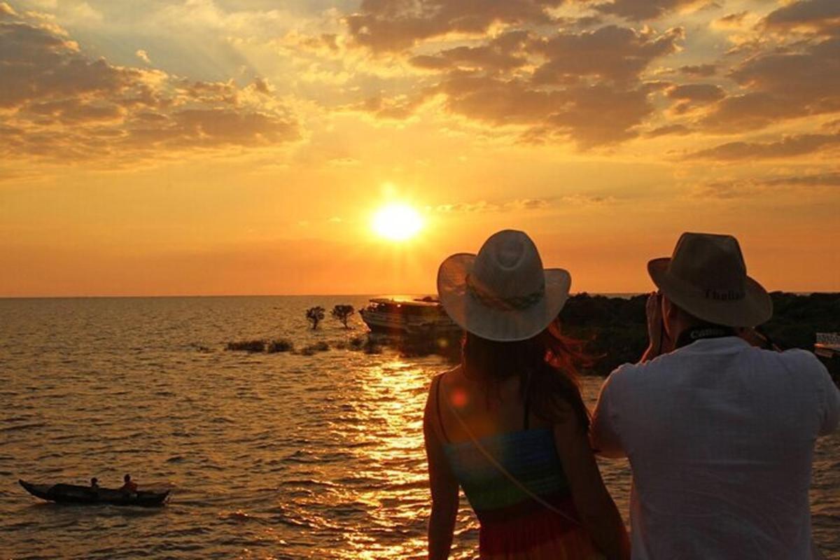 Dos personas mirando la puesta de sol sobre el agua.