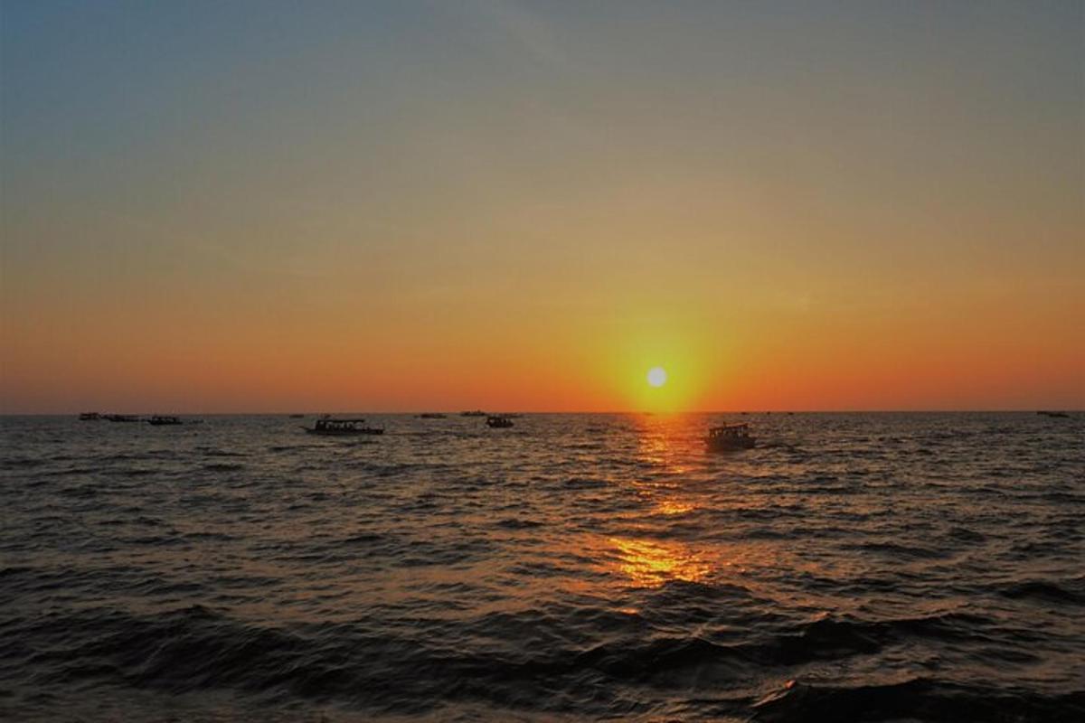 um pôr do sol sobre o oceano com barcos na água