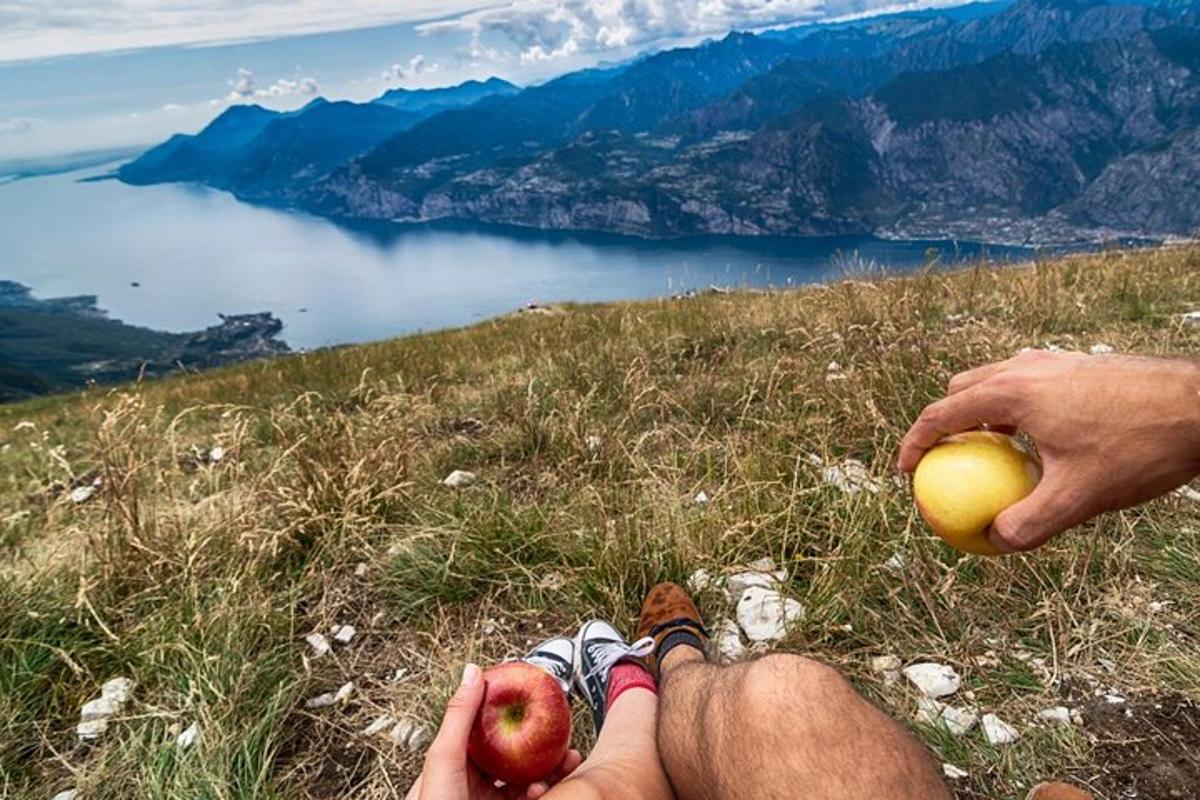 osoba sedící na vrcholu hory a držící jablko