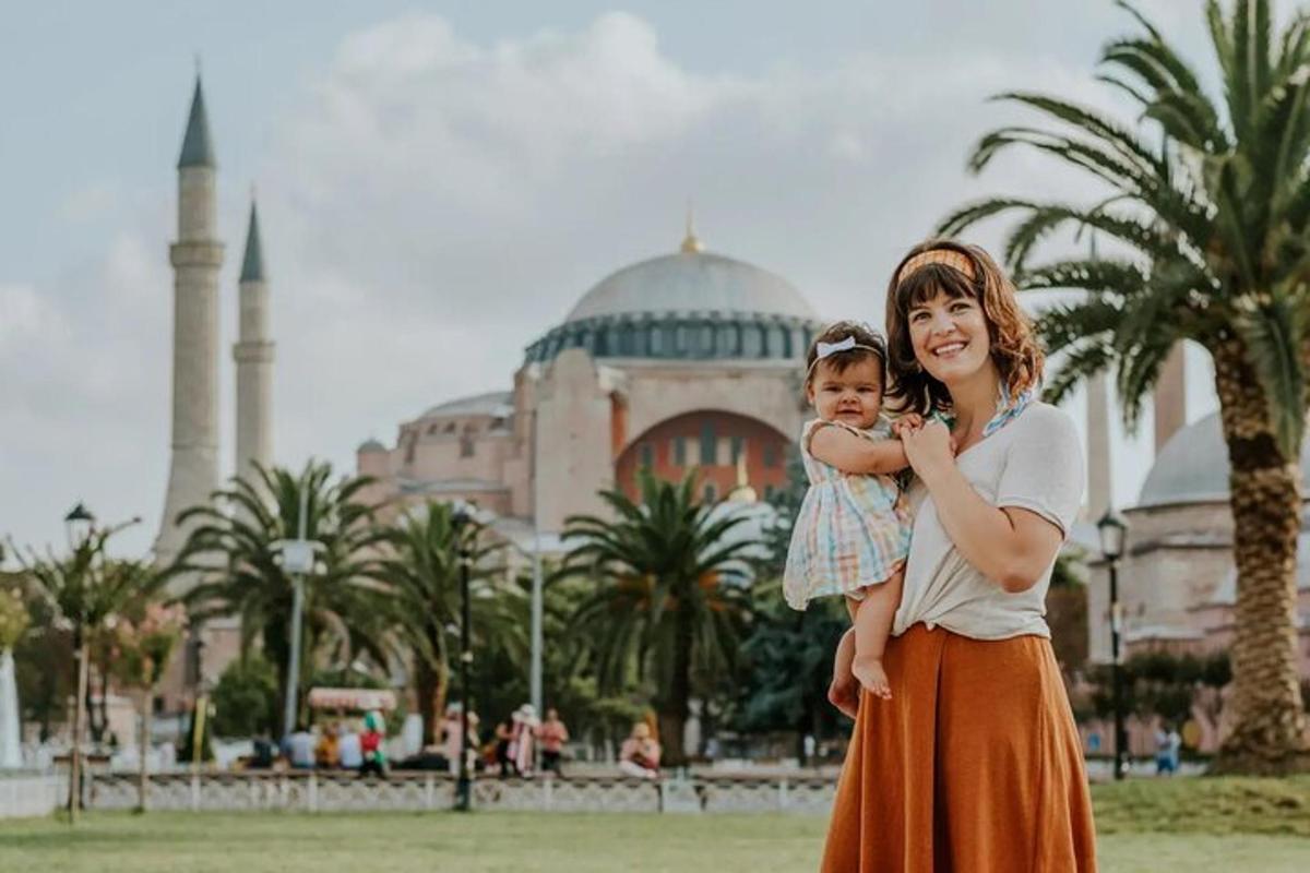 seorang wanita menggendong kanak-kanak di hadapan masjid