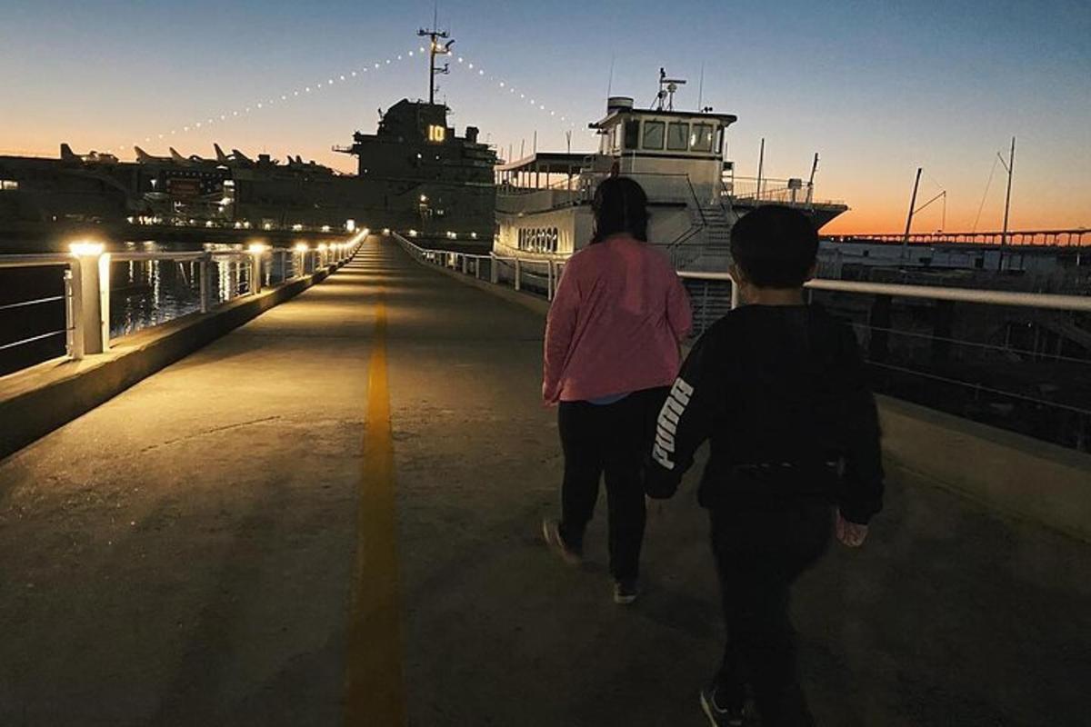 two people walking down a bridge at sunset