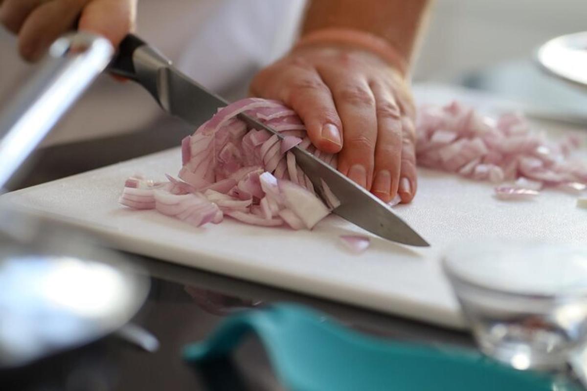 una persona che taglia la carne su un tagliere con un coltello
